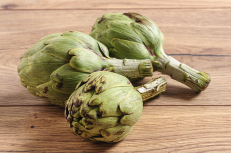 A closeup of artichokes on a wooden table with a blurry backgroundの写真素材