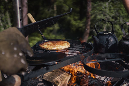 A closeup of a delicious pancake cooking over the campfire outdoorsの写真素材