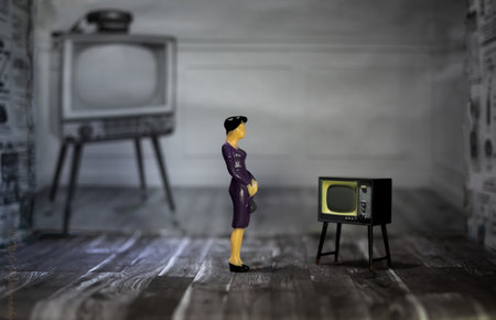 A closeup shot of a miniature person figure in a room with a vintage TVの写真素材