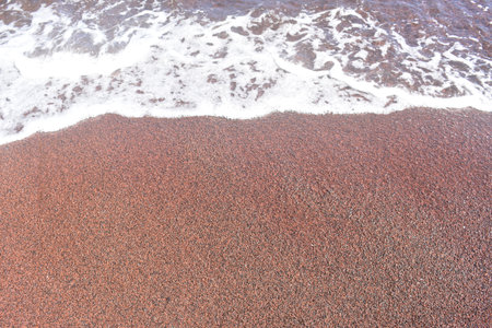 An ocean splashing up on the red sand beach on the island of Maui, Hawaiiの写真素材