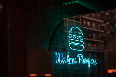A turquoise LED welcome burgers sign on metal netの写真素材