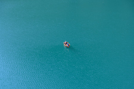 An aerial shot of a boat with two people in a calm blue seaの写真素材