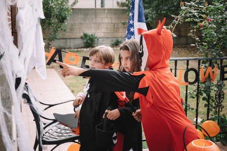 Costumed kids trick-or-treating on Halloween in a decorated houseの写真素材