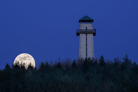 A beautiful shot of a whole full supermoon behind the Tisnov city observatory in the Czech Republicの写真素材