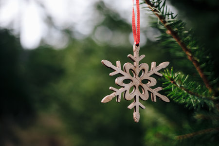 A wooden Christmas hanger in form of a snowflake hanging on a fir tree