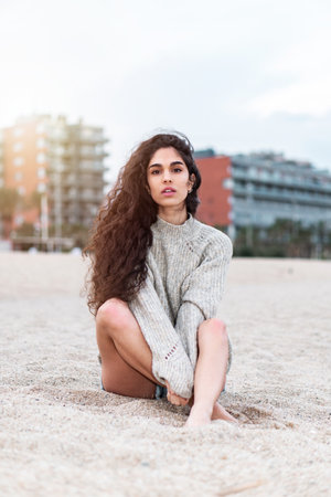 A vertical shot of a young female sitting on a beachの写真素材
