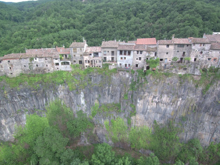 An ancient small town Castellfollit de la Roca on a cliff surrounded by lush vegetation in Spain