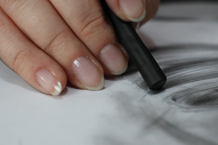 A closeup of a female artist drawing  on a paper with a charcoal pencilの写真素材