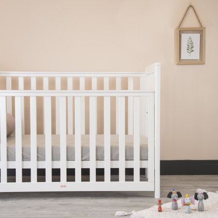 A modern baby room interior with a cozy classic crib and miniature toys placed on a soft carpetの写真素材