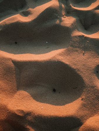A vertical shot of texture of sand in a wave mode on the coast of the seaの写真素材