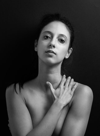 A vertical grayscale shot of a beautiful young lady posing toplessの写真素材
