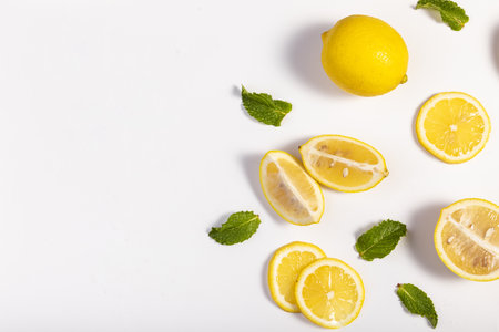 A flat lay of lemon and mint herbs on a white backgroundの写真素材
