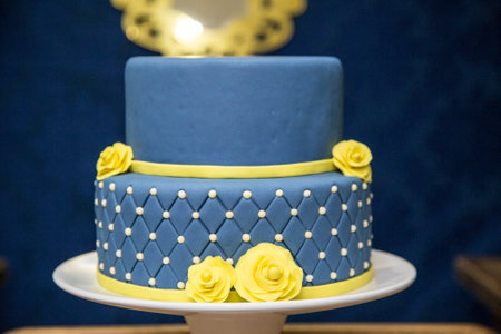 A selective focus shot of a blue fondant cake with yellow flowers design on a trayの写真素材