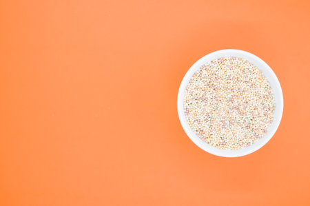 A high angle shot of a bowl of cornflakes on an orange surface
