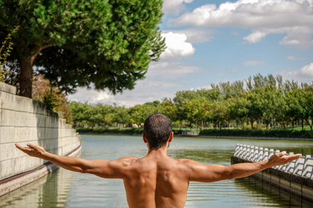 A shallow focus of a male meditating in a pond surrounded by greenery under the sunlightの写真素材