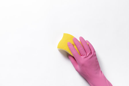 A top view closeup of a rubber glove and a sponge on a white background