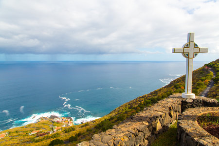 A closeup shot of a cross on a hill facing the seaの写真素材
