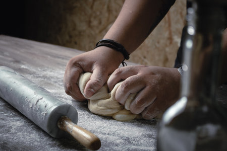 A closeup shot of a baker mixing the dough with flourの写真素材