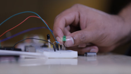 Electronic components connecting in Breadboard, a hand of technician holds led light