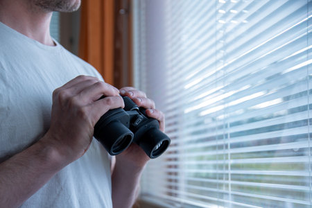 A selective focus shot of male hands holding black binocularsの写真素材