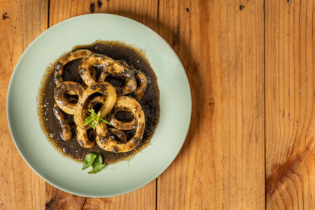 A top view of a plate of delicious calamari prepared with ink and saucesの写真素材