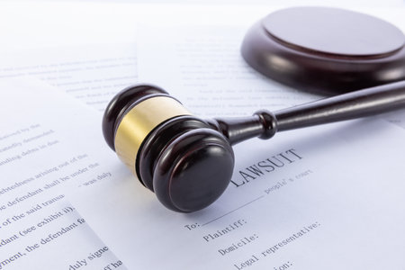 A closeup shot of a gavel and lawsuit papers on a white surfaceの写真素材