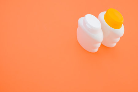 A top view closeup of two bottles with closed caps isolated on an orange background