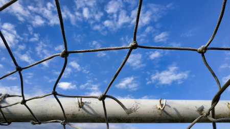 A closeup of a soccer net under the sunlight and a blue sky at daytime
