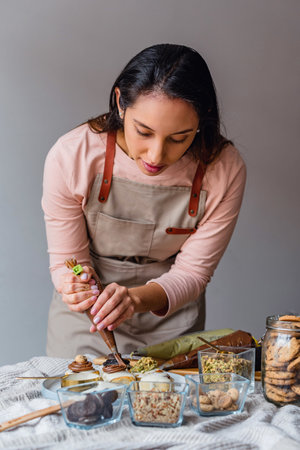 A Hispanic woman preparing and decorating cinnamon rollsの写真素材