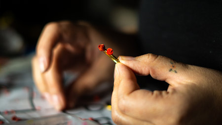 A closeup of a woman's hand holding a custom handmade golden ring with two red roses on it