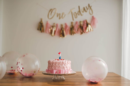 A pink birthday cake with number 1 candle on it decorated with edible creamy roses - decorations for birthdayの写真素材