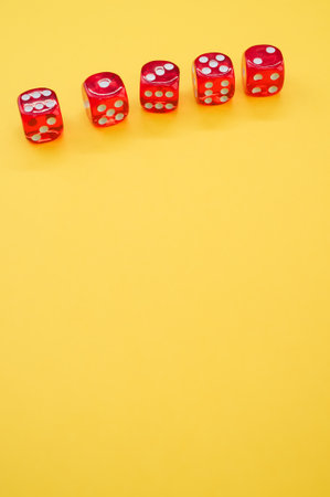 A vertical high angle shot of playing dice on an isolated yellow backgroundの写真素材