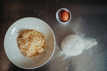 A closeup shot of grated cheese, dough, and an eggの写真素材