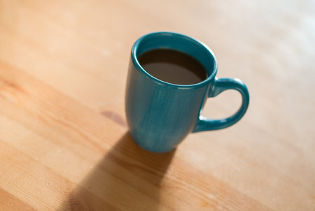 A cozy morning with a cup of coffee sitting on a wooden table.の写真素材