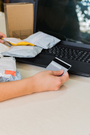 A close up view of woman's hand holding credit card and making online purchase using laptop