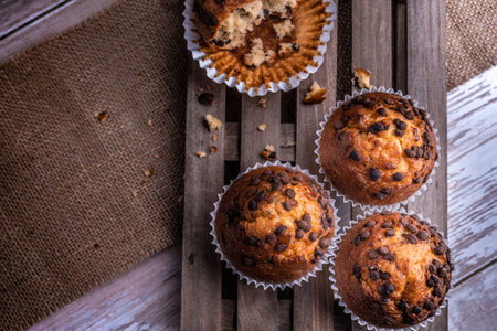 A top view of the freshly baked cupcakes with chocolate chips on a wooden trayの写真素材