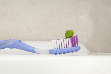 A selective focus shot of green toothpaste squeezed on the colorful toothbrushの写真素材
