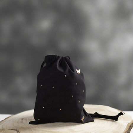 A black hygiene draw-string bag dotted with stars, displayed on a wooden discの写真素材