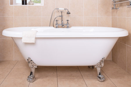 A closeup of a luxury vintage bathtub with a shiny metal faucetの写真素材