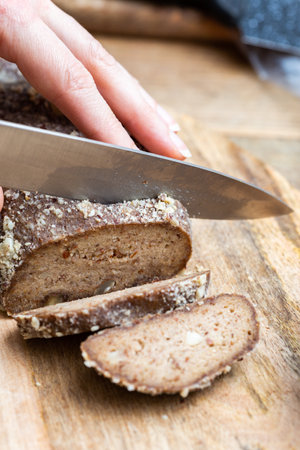 A person slicing raw vegan bread with a knife