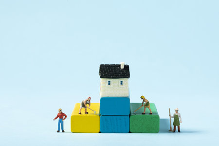 A beautiful shot of a toy house and people cleaning aroundの写真素材