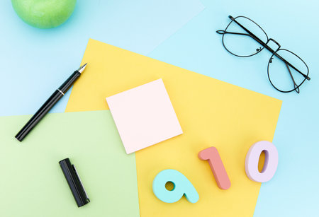 A top view of 910 number with ballpen, piece of paper, and eyeglass isolated on a blue surfaceの写真素材