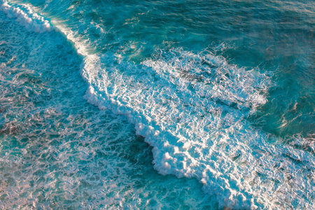 A high angle shot of sea waves under the sunlight in Bali, Indonesiaの写真素材