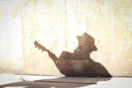 A beautiful shot of a guitar player shadow on a wallの写真素材