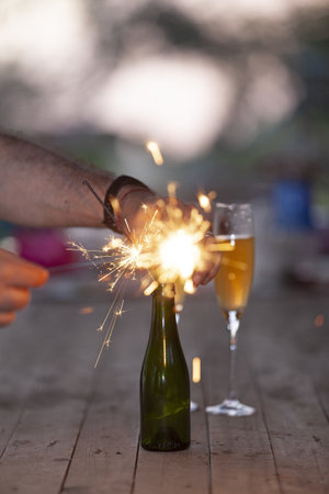 A vertical shot of a man lighting up sparklers in a bottleの写真素材