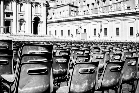 A grayscale shot of black plastic chairs in a square in Romeの写真素材