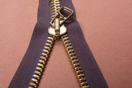 A closeup shot of a zipper on a brown surfaceの写真素材