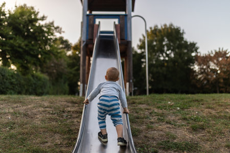A young boy climbing up on a slide