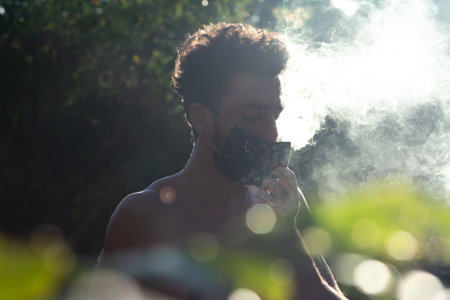 A young Hispanic male wearing a face mask and walking in the outdoors under sunlight