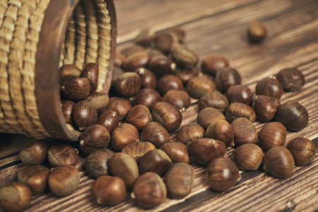 Fresh chestnuts in the basket falling on a brown wooden tableの写真素材